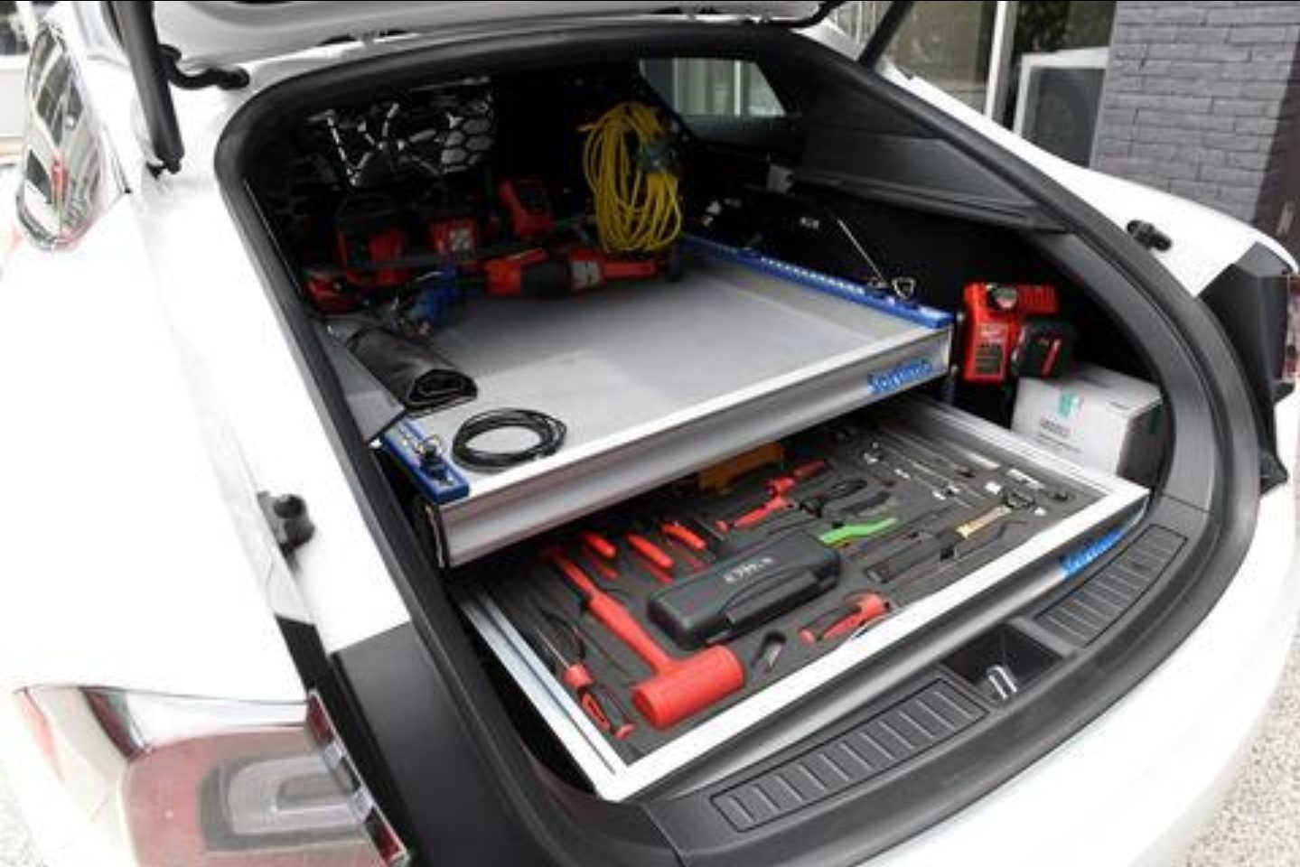 Tesla cargo area with slide-out foam tool trays and power tools organized for the road